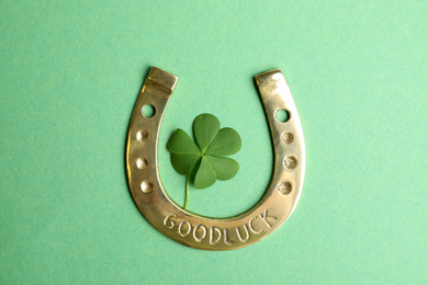 Photo of Clover leaf and horseshoe on green background, flat lay. St. Patrick's Day celebration