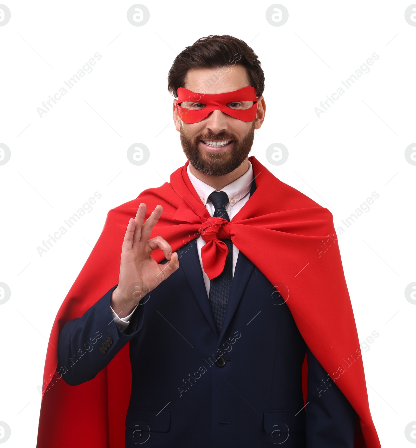 Photo of Happy businessman in red superhero cape and mask showing ok gesture on white background