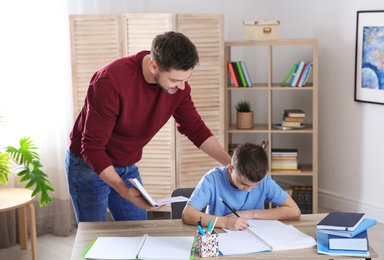 Dad helping his son with homework in room