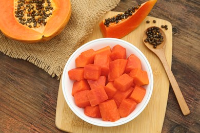 Photo of Tasty cut papaya fruits on wooden table, flat lay