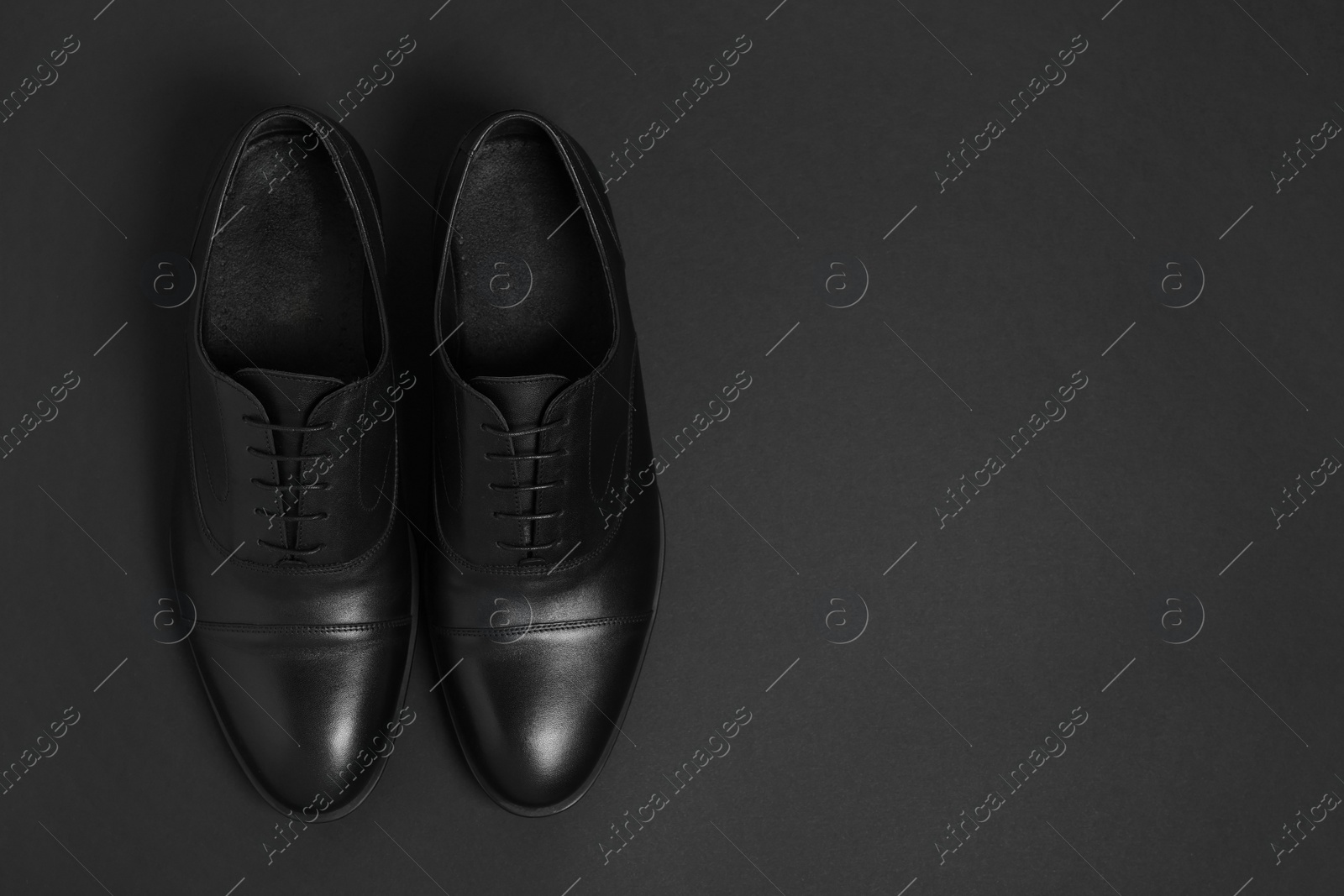 Photo of Pair of leather men shoes on black background, top view. Space for text