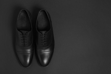 Photo of Pair of leather men shoes on black background, top view. Space for text