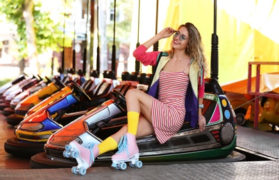 Happy girl with retro roller skates sitting in entertainment park