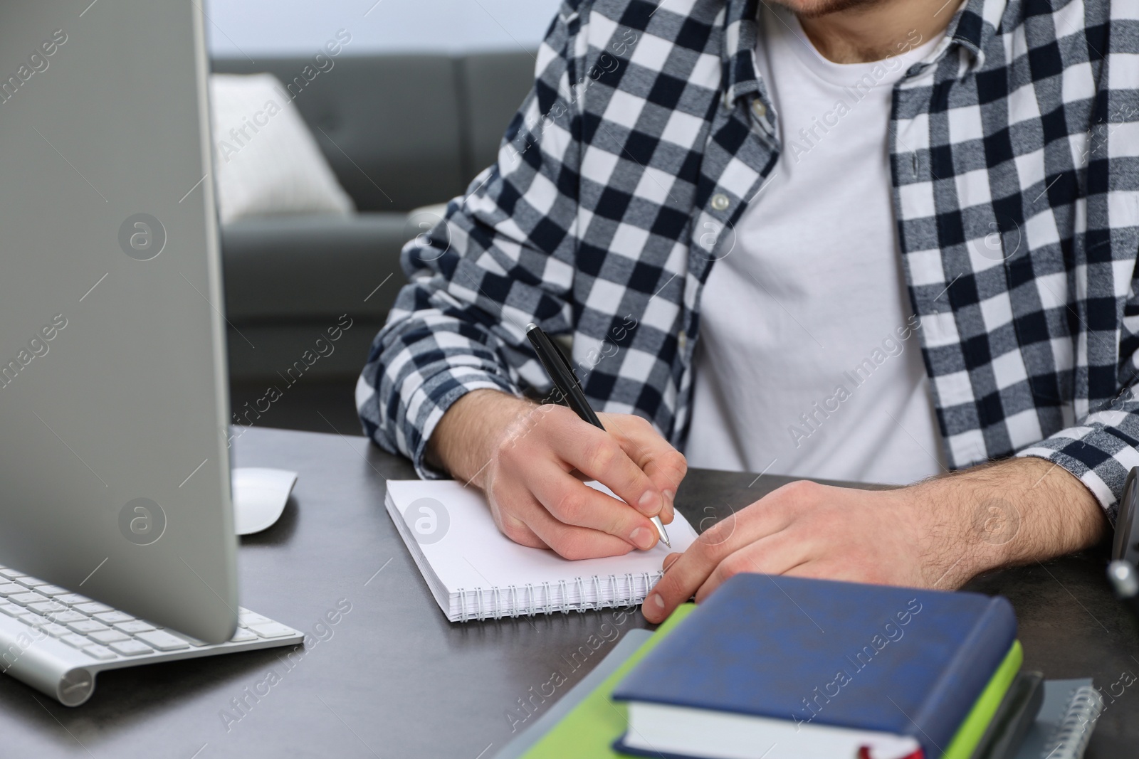 Photo of Young man using modern computer for studying at home, closeup. Distance learning