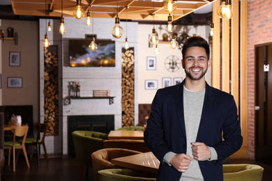 Young business owner standing in his cafe. Space for text
