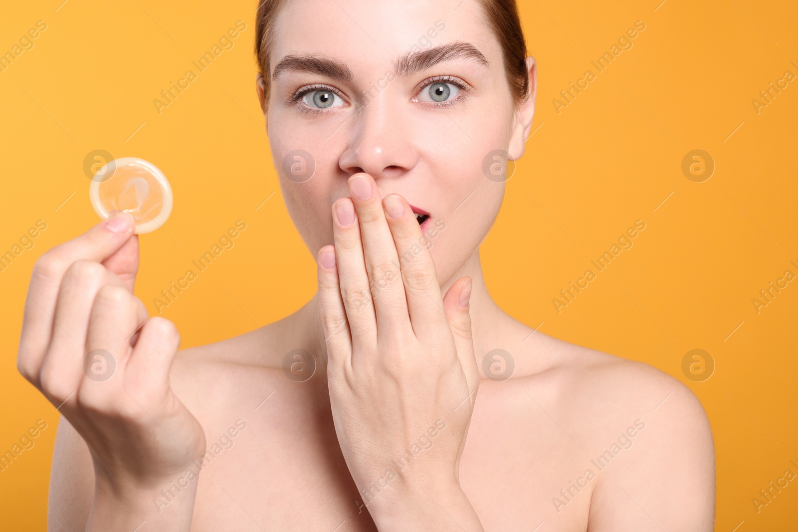 Photo of Woman holding condom on yellow background. Safe sex