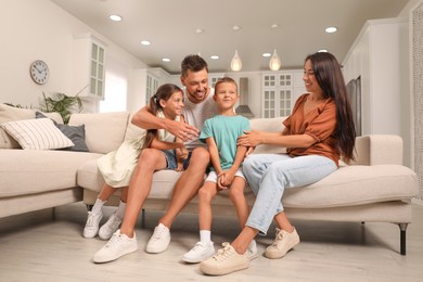 Photo of Happy family with children having fun on sofa at home