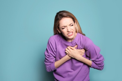 Photo of Young woman having heart attack on color background