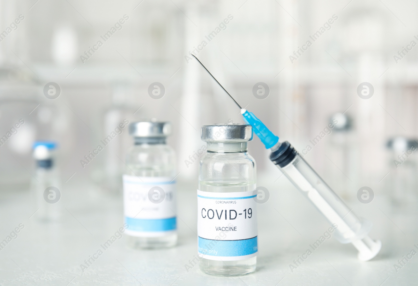 Photo of Vials and syringe with coronavirus vaccine on light table