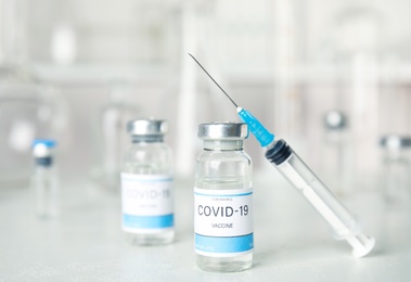 Photo of Vials and syringe with coronavirus vaccine on light table