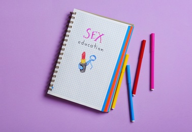 Photo of Notebook with phrase "SEX EDUCATION" on violet background, flat lay