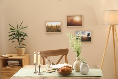 Photo of Clean tableware, candlesticks, flowers and fresh pastries on table in stylish dining room