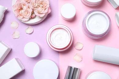 Flat lay composition with different skin care products and flowers on color background