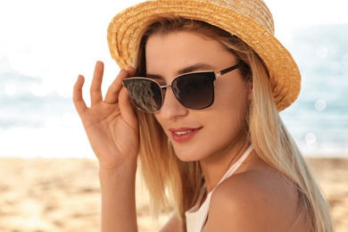 Beautiful woman wearing sunglasses at beach on sunny day