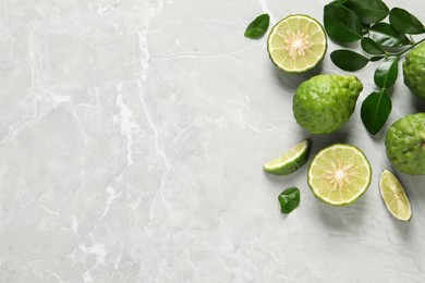 Photo of Fresh ripe bergamot fruits with green leaves on light grey marble table, flat lay. Space for text
