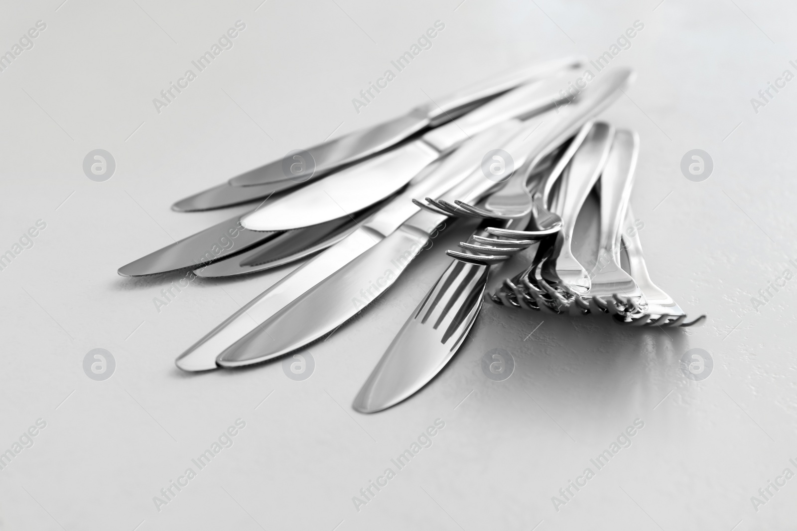 Photo of Knives and forks on white table, closeup