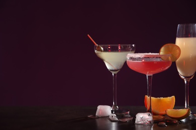 Photo of Many different alcoholic drinks on table against dark background. Space for text