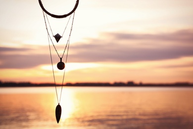 Photo of Magical amulet against river at sunset, space for text. Healing concept