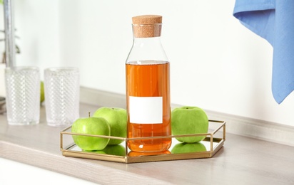 Photo of Bottle with juice and fresh apples in kitchen