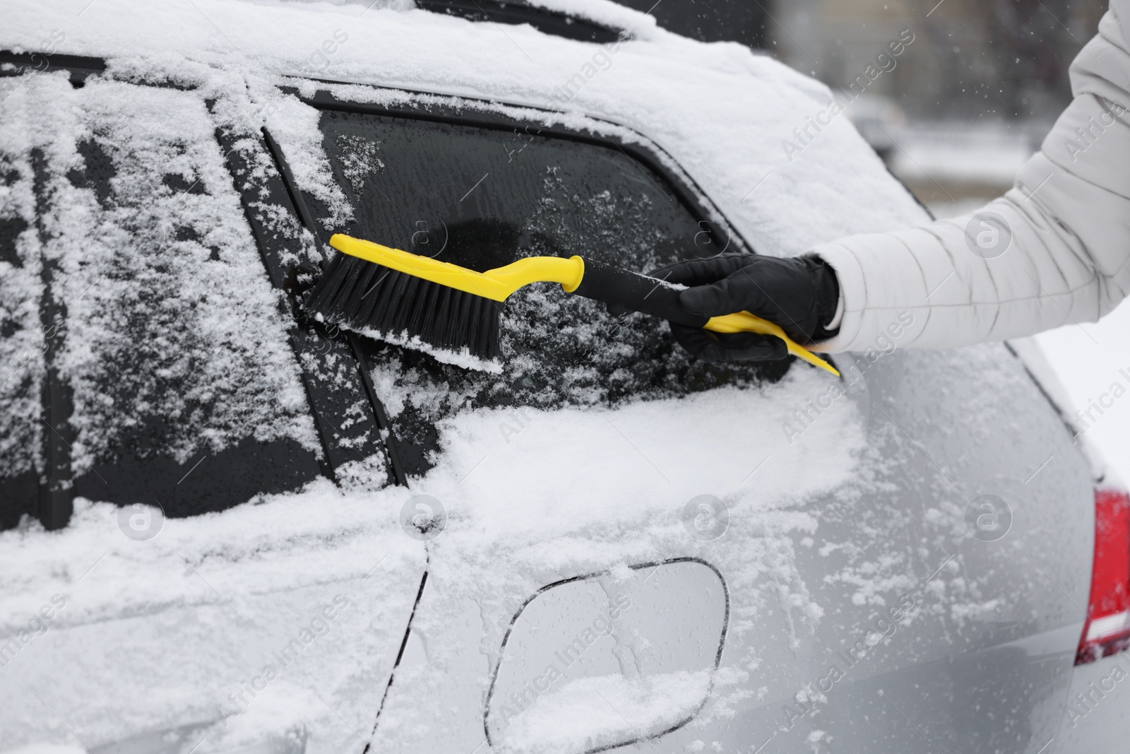 Photo of Man cleaning snow from car outdoors, closeup