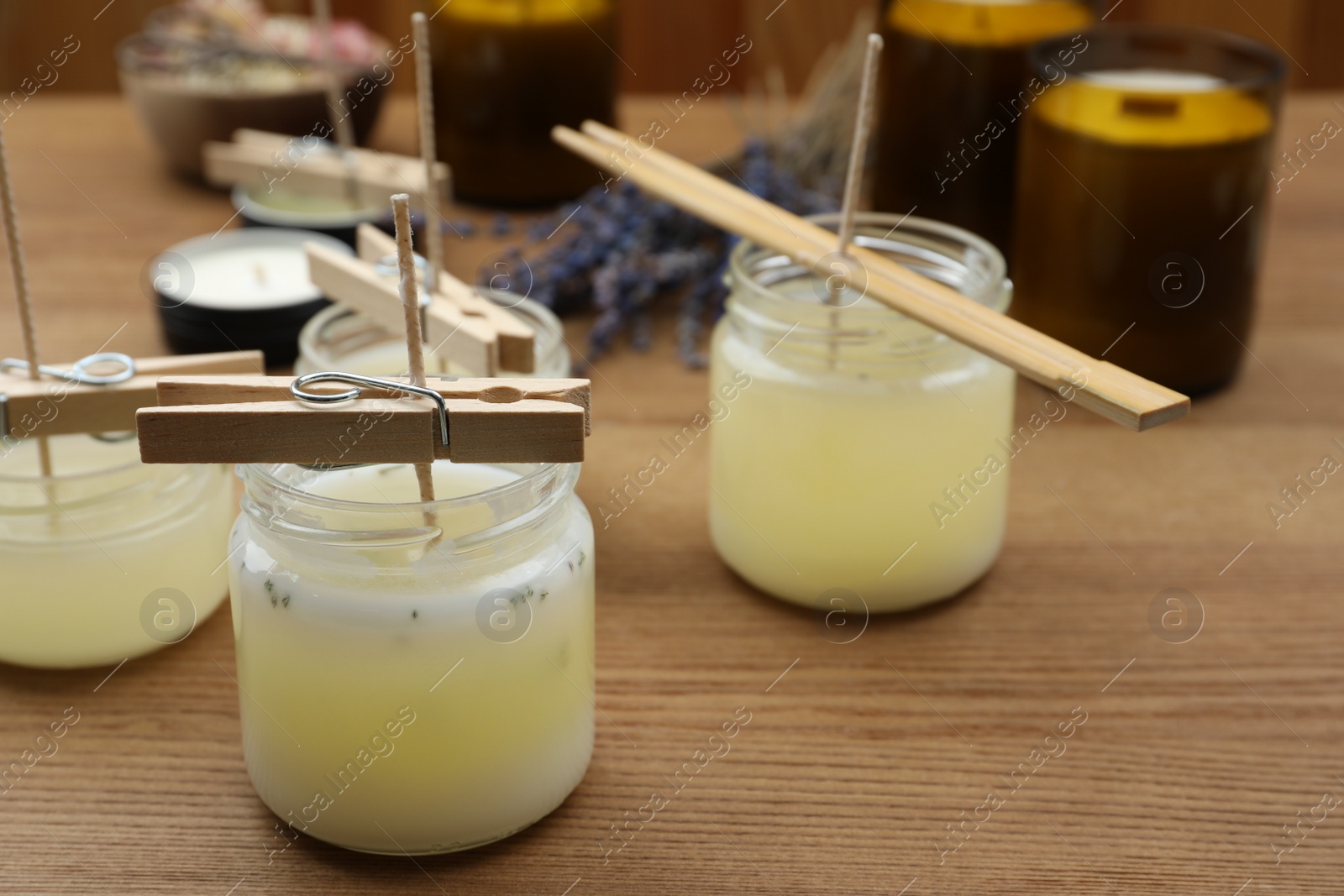 Photo of Glass jars with wax on wooden table, space for text. Handmade candles