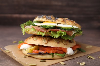 Stacked tasty bagel sandwiches on brown table, closeup