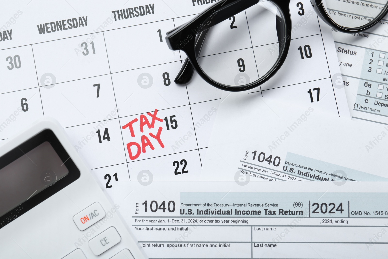 Photo of Calendar with date reminder about tax day, documents, glasses and calculator, top view