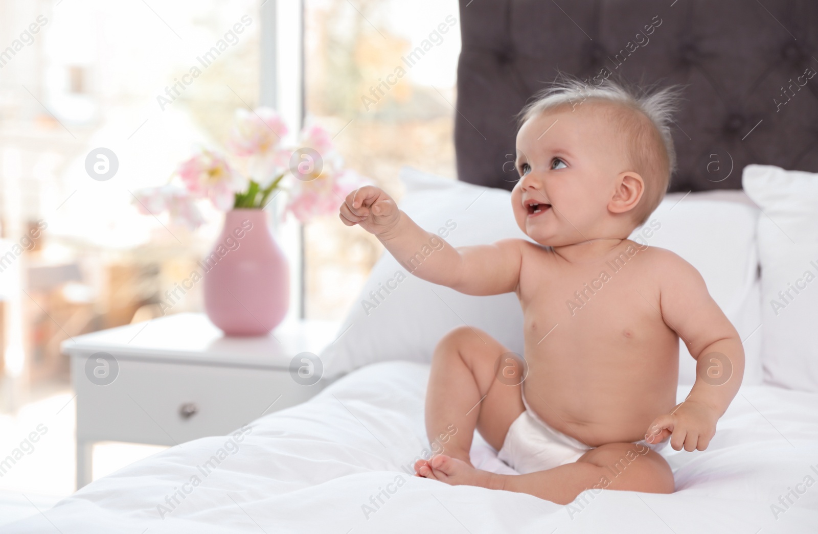 Photo of Cute baby in diaper on bed at home. Space for text