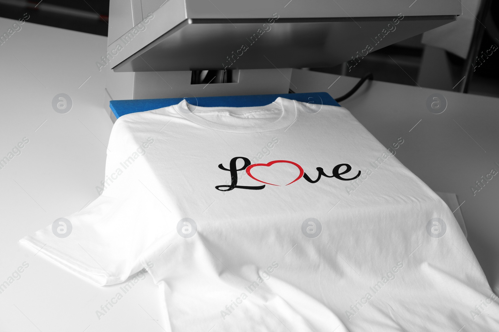 Photo of Printing logo. Heat press with t-shirt on white table