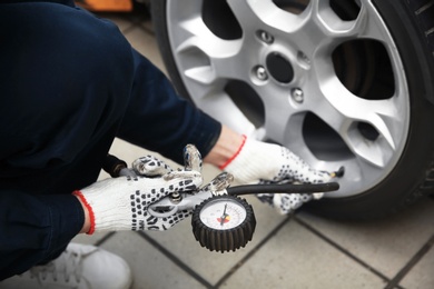 Mechanic checking tire pressure in service center, closeup