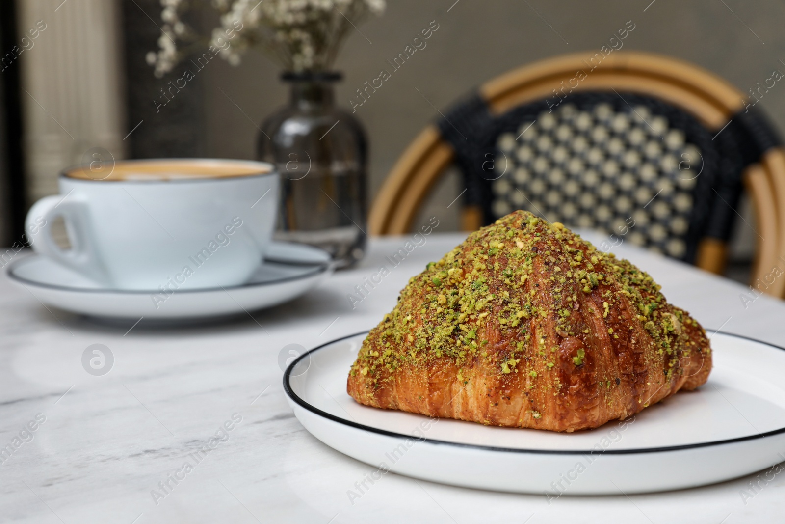 Photo of Delicious croissant on white marble table in cafe, space for text