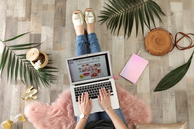 Woman and laptop with open fashion blogger site on floor, top view