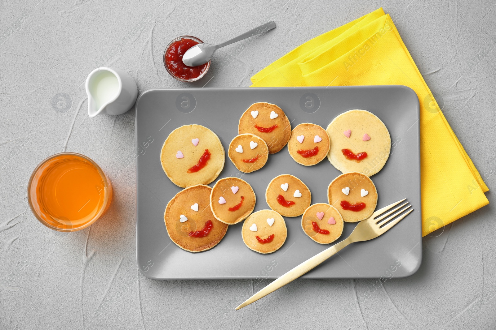 Photo of Flat lay composition with smiling pancakes on grey background. Creative breakfast ideas for kids