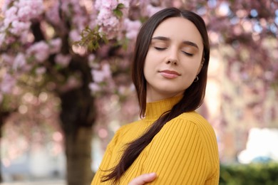 Photo of Beautiful woman near blossoming tree on spring day, space for text