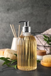 Photo of Stylish dispenser with liquid soap and other bathroom amenities on dark table