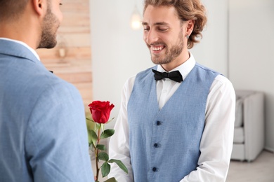 Happy newlywed gay couple with flower at home