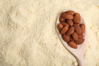 Photo of Spoon with almonds on flour, top view. Space for text