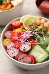 Photo of Bowl with many different vegetables on white wooden table, closeup. Vegan diet