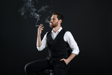 Photo of Man using cigarette holder for smoking on black background