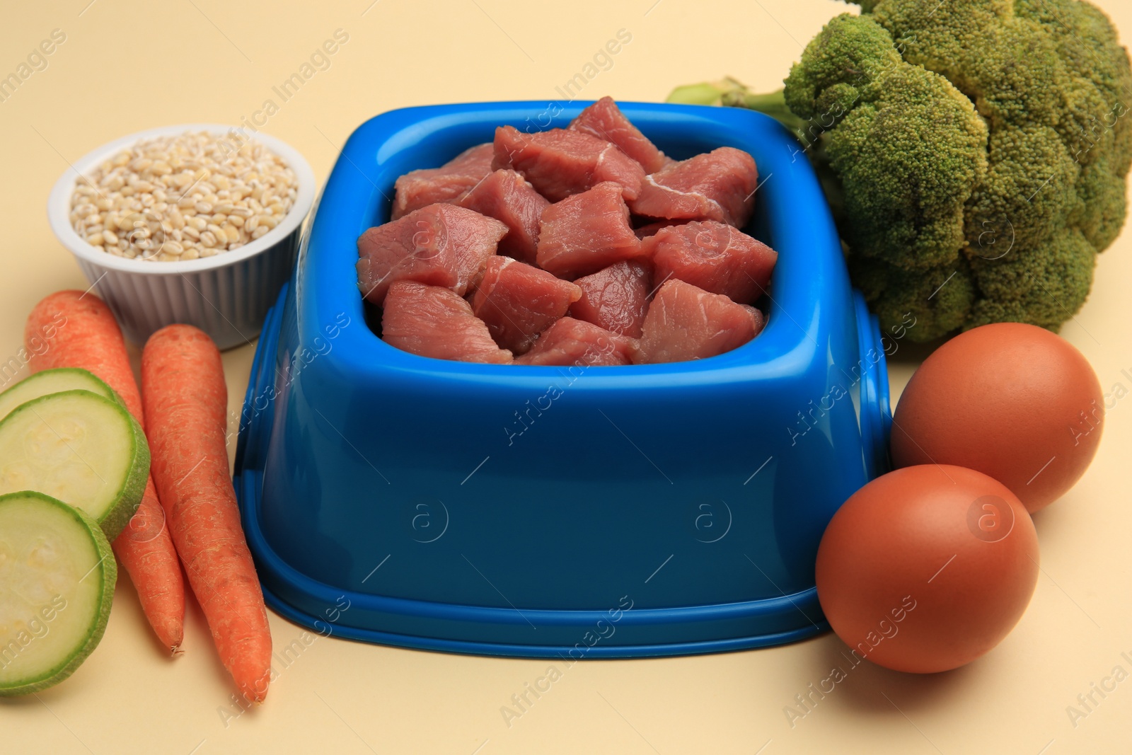 Photo of Raw meat in bowl and healthy products for pet on beige background, closeup