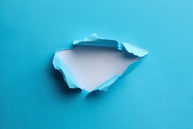 Photo of Hole in light blue paper on white background