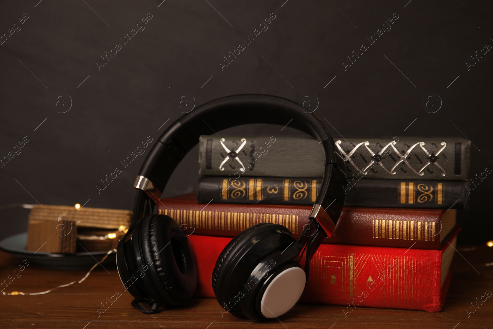 Photo of Books and headphones on wooden table against black background