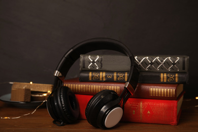 Photo of Books and headphones on wooden table against black background