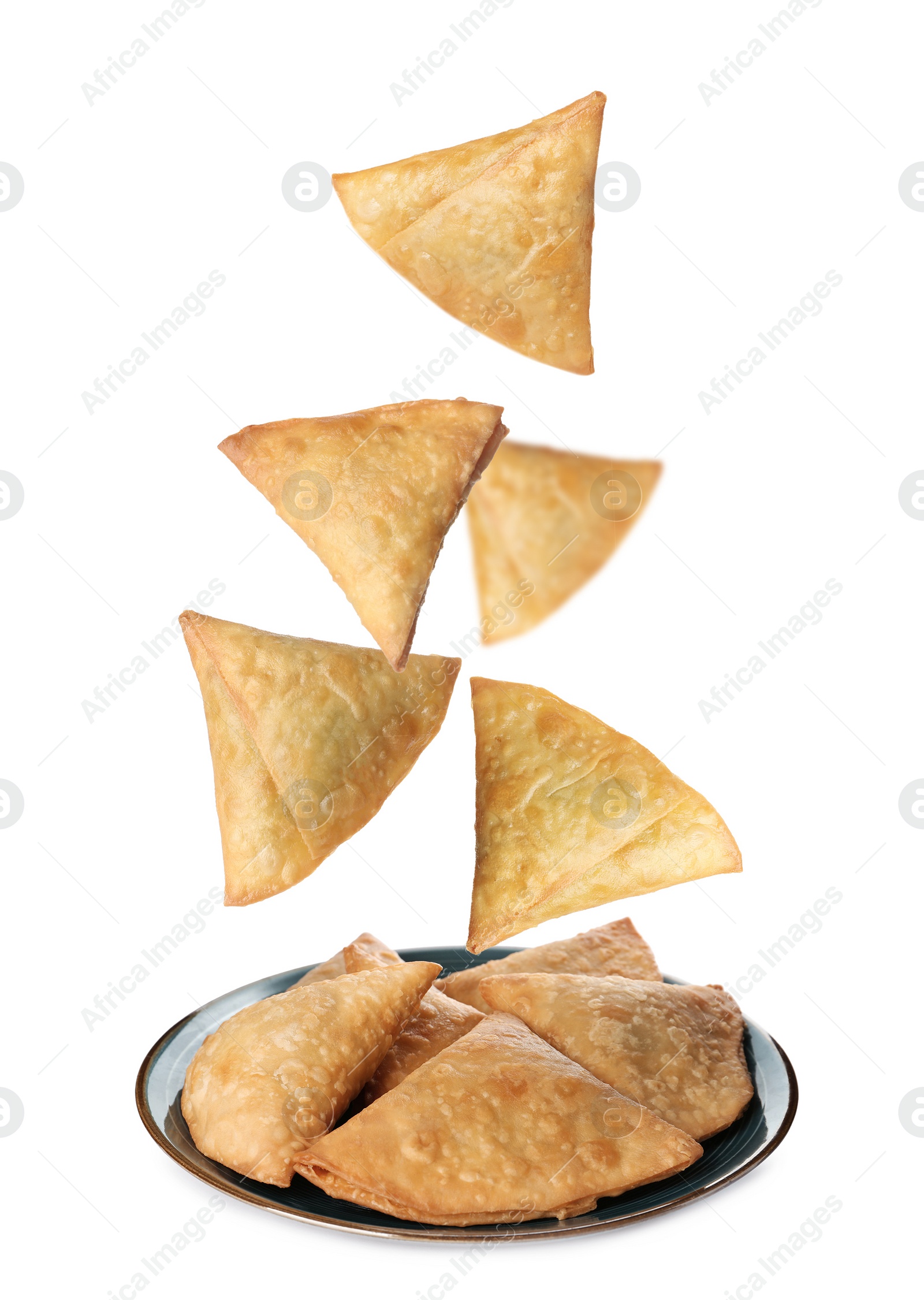 Image of Crispy delicious samosas falling into plate on white background