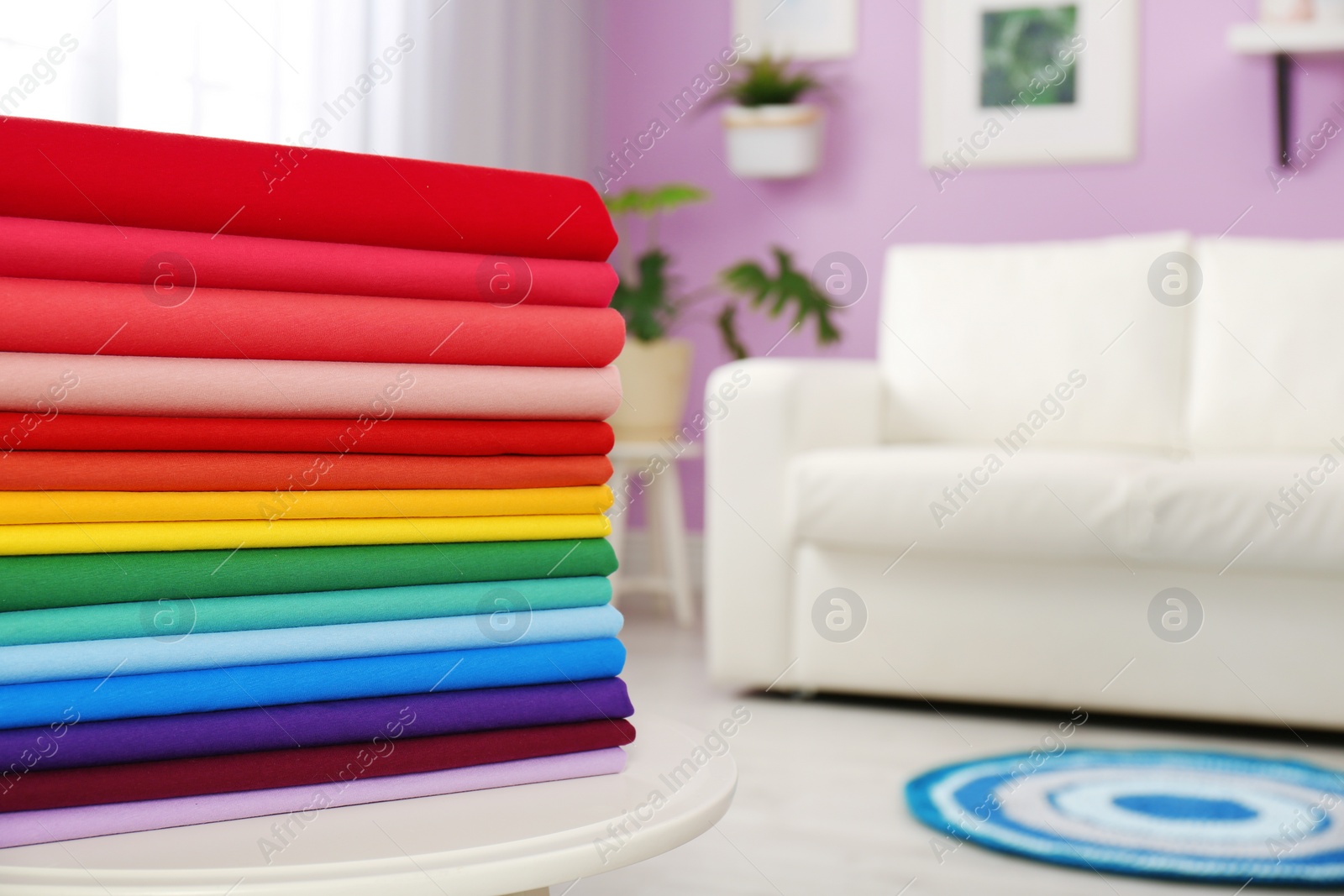 Photo of Pile of colorful t-shirts on table in living room