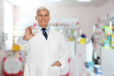Professional senior pharmacist with pills in modern drugstore 