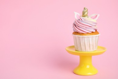 Photo of Dessert stand with cute sweet unicorn cupcake on pink background. Space for text