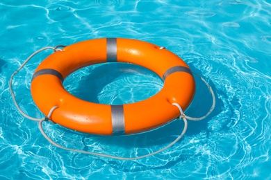 Photo of Lifebuoy floating in swimming pool on sunny day