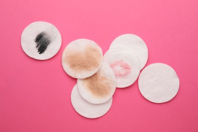 Photo of Clean and dirty cotton pads after removing makeup on pink background, flat lay