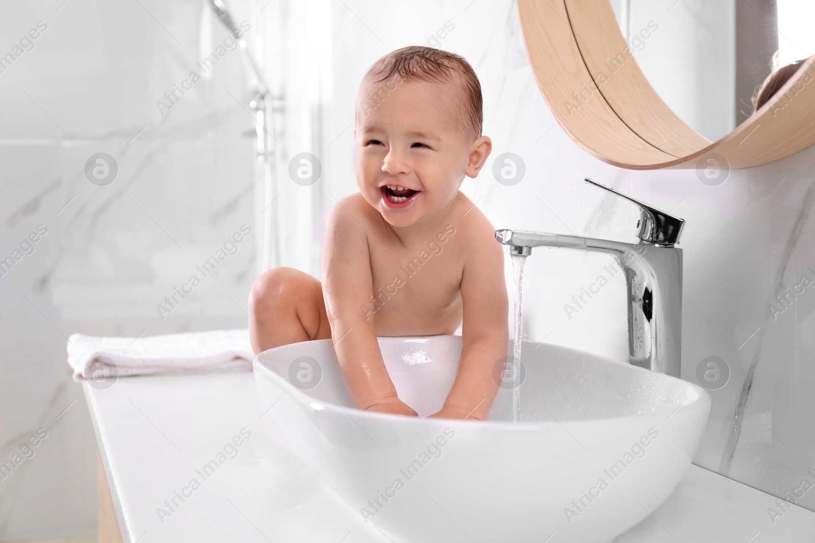 Photo of Cute little baby playing in bathroom at home